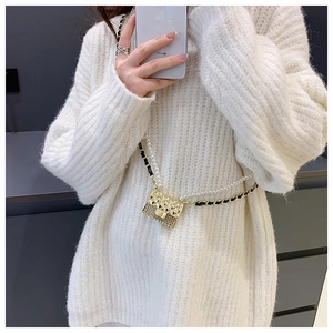 Detail of gold mini quilted bag with pearl strap and woven chain on white knit sweater