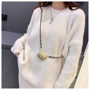 Detailed view of mini gold quilted bag with pearl and chain strap on a soft mohair sweater