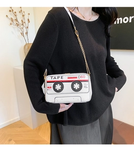 Detail of creative vintage cassette tape crossbody bag with gold chain and white PU leather