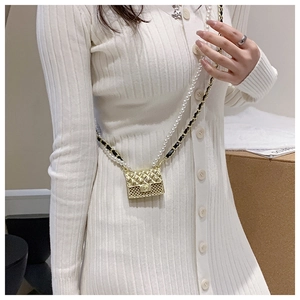 Detail of mini gold quilted crossbody bag with pearl strap and metal chain on model