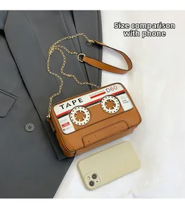 Detail of vintage cassette-shaped crossbody bag in brown faux leather with gold chain strap