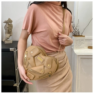 Khaki heart-shaped crossbody bag with moto jacket zipper details on a model