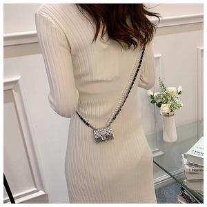 Detail view of silver quilted mini bag with pearl chain strap worn as a crossbody accessory