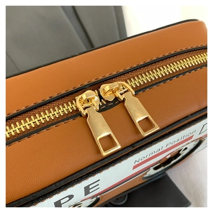 Detail of vintage tape camera bag showing golden double zippers and lychee texture