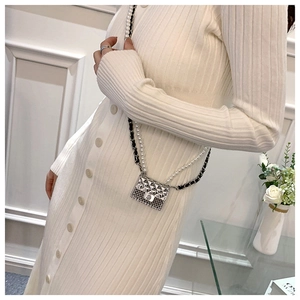Detail shot of a silver mini quilted bag with pearl chain on a white dress