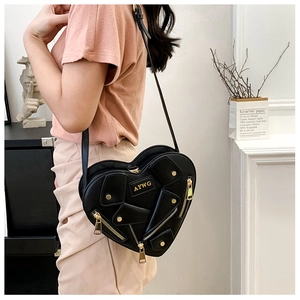 Model wearing a black heart-shaped crossbody bag with motorcycle jacket details and gold hardware