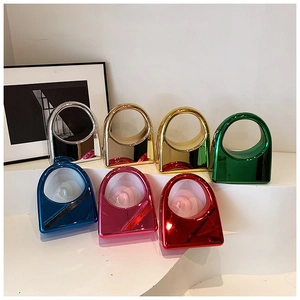 Row of mini metallic hardshell evening bags in seven bright candy colors with round handles