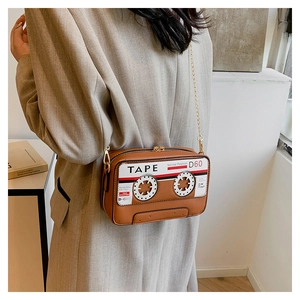 Detail of vintage brown tape-shaped crossbody bag with gold chain on grey blazer