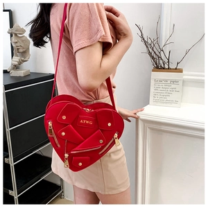 Detail of red heart-shaped jacket design crossbody bag with metallic zippers and hardware