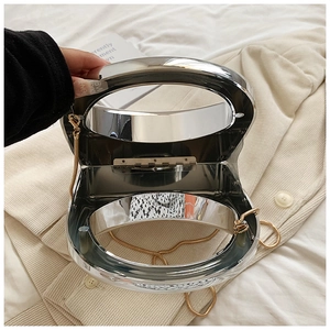 Detail view of silver mirror box bag showing hinge mechanism and golden chain strap