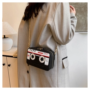 Detail of creative vintage cassette tape shoulder bag with gold chain strap on a model
