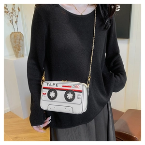 Detailed view of a white cassette tape shaped crossbody bag with elegant gold chain strap