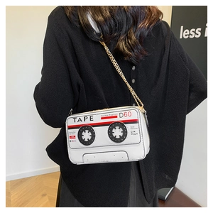 Detail of white retro cassette tape crossbody bag worn by model with gold chain strap