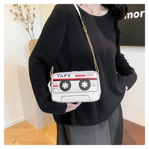 Macro detail of retro cassette tape shaped crossbody bag with gold chain and white PU leather