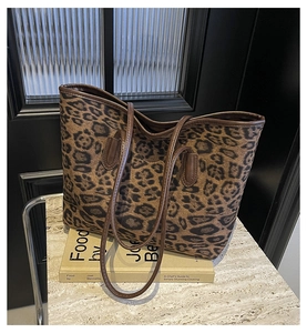 Detail of leopard print tote bag with brown straps placed on a decorative book