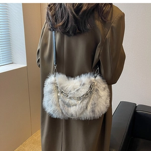 Detail of grey faux fur crossbody bag with decorative silver chains on brown blazer