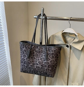 Detailed view of leopard print tote bag with black leather handles hanging on a rack