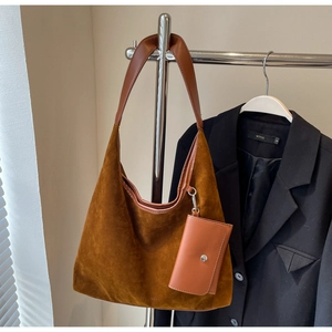 Brown suede hobo tote bag with matching detachable pouch hanging on a metal rack