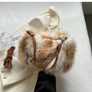 Detailed top view of spotted faux fur bag with silver chains and leather strap on white fabric
