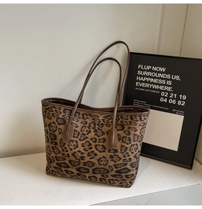 Detailed close-up of leopard print tote bag with brown leather trim on marble surface