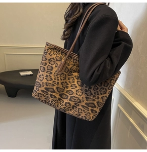 Detail of a large leopard print tote bag with brown leather straps on a model's shoulder