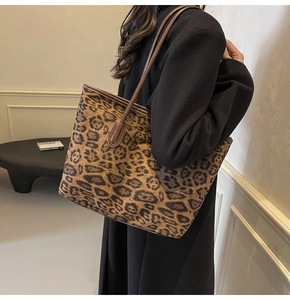Detail of large capacity leopard print tote bag with brown leather handles on shoulder