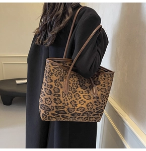 Detail of a large leopard print tote bag with brown straps shown on shoulder