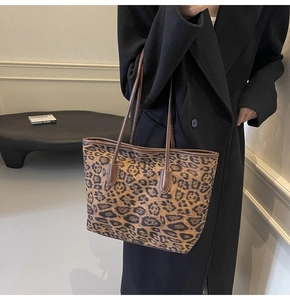 Detailed side view of large leopard print tote bag with brown leather straps and trim