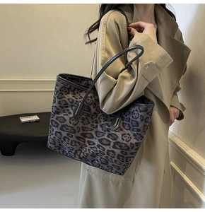 Detailed view of a large leopard print tote bag with black leather straps on a model