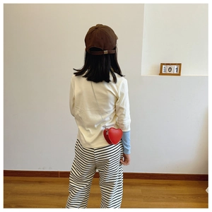 Vista posteriore di un bambino con una borsa a tracolla rossa a forma di cuore e catena