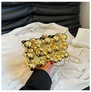 Detail of gold metallic sphere evening bag with elegant white pearl strap handle