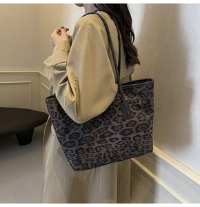 Model wearing a large leopard print tote bag with black leather straps and canvas texture