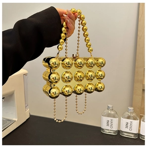 Detail of gold egg-shaped handbag with polished spheres and pearl metal handle