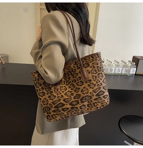 Detail of leopard print tote bag featuring brown leather straps and canvas texture