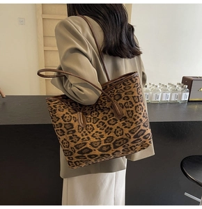 Macro detail of high-capacity leopard print tote bag with brown leather handles and vintage style