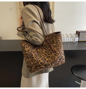 Detail of vintage leopard print tote bag with brown leather straps worn on shoulder