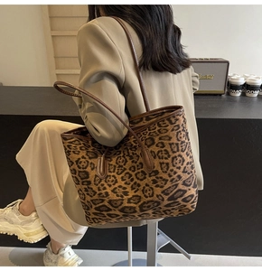 Detailed macro view of large leopard print tote bag with brown leather shoulder straps