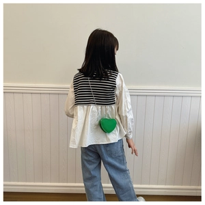 Dettaglio di una borsa a tracolla verde a forma di cuore per bambini con catena