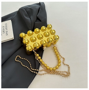 Detail of gold egg-shaped evening bag with mirrored spheres and metallic bead chain
