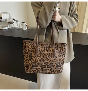 Close-up of leopard print tote bag styled with a khaki blazer in a chic cafe setting