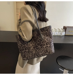 Detail of leopard print tote bag with black slender shoulder straps and canvas texture