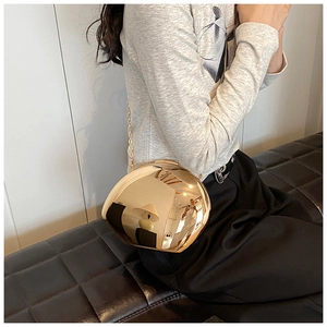 Dettaglio di una borsa a sfera oro specchiato alla moda con sottile tracolla a catena