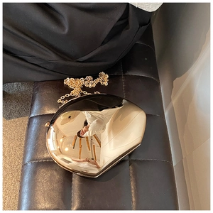 Dettaglio borsa box a specchio in acrilico oro lucido con raffinata catena in metallo su pelle