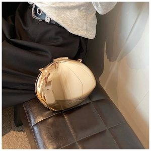 Dettaglio di una pochette in acrilico dorato a forma di uovo con finitura in metallo