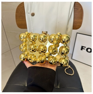 Detail of gold egg-shaped clutch bag with textured metal spheres and beaded chain strap