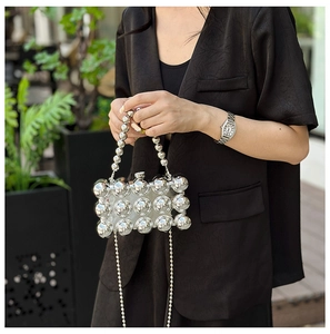 Close-up of a silver egg-shaped clutch bag with polished spheres and metallic chain