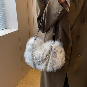 Plush faux fur underarm bag with silver chain strap shown on a green trench coat