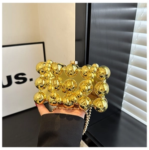 Detailed view of the gold dinner clutch bag with decorative metallic spheres and bead chain