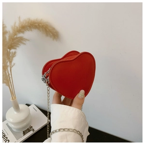 Dettaglio della mini borsa a tracolla rossa a forma di cuore con catena e cerniera