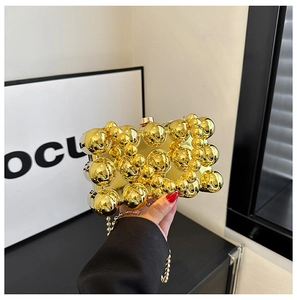 Detail of gold evening clutch bag featuring 3D metallic beads and reflective mirror surface